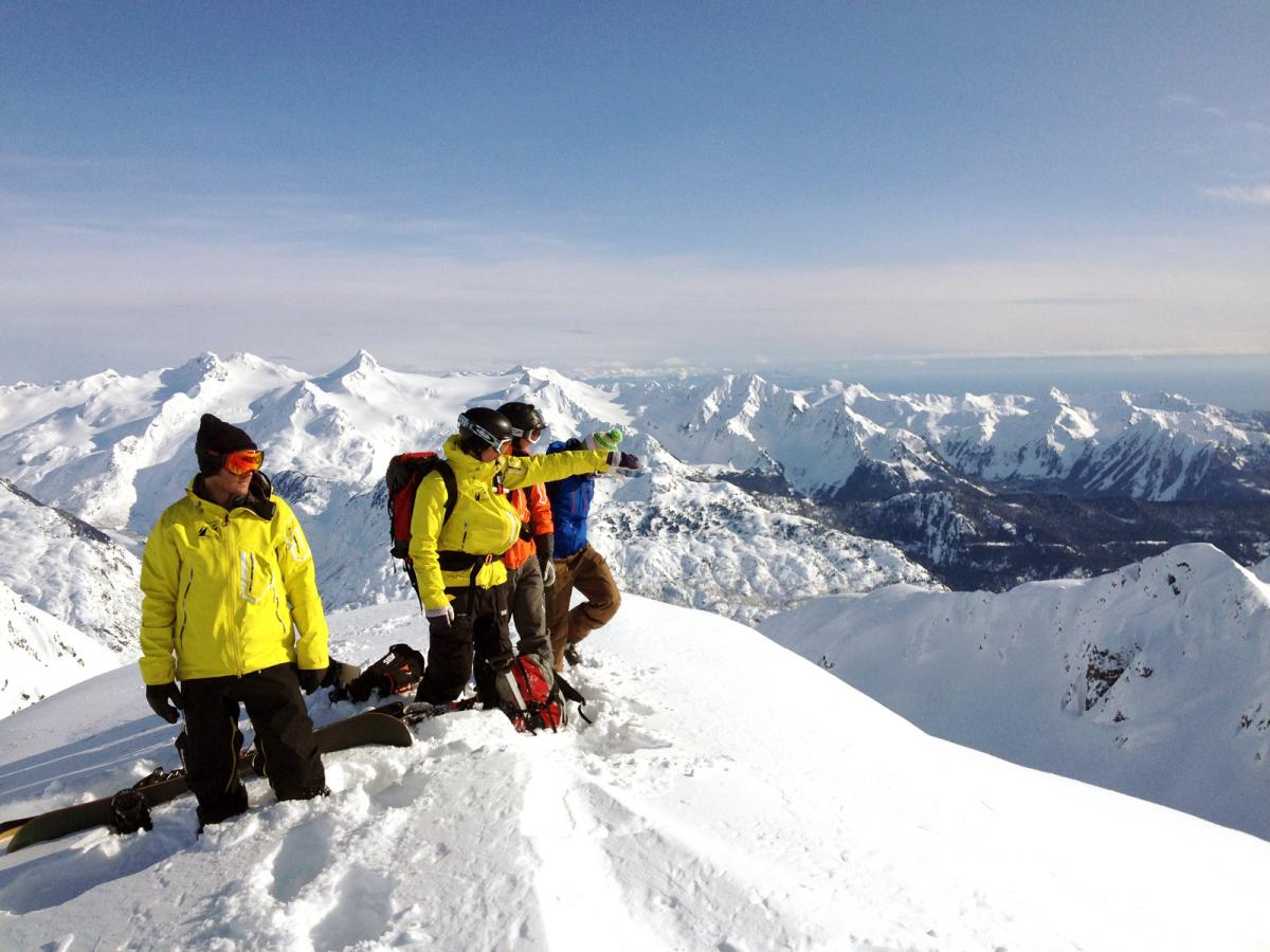 A group standing on top of a peak getting ready to drop into their next line.